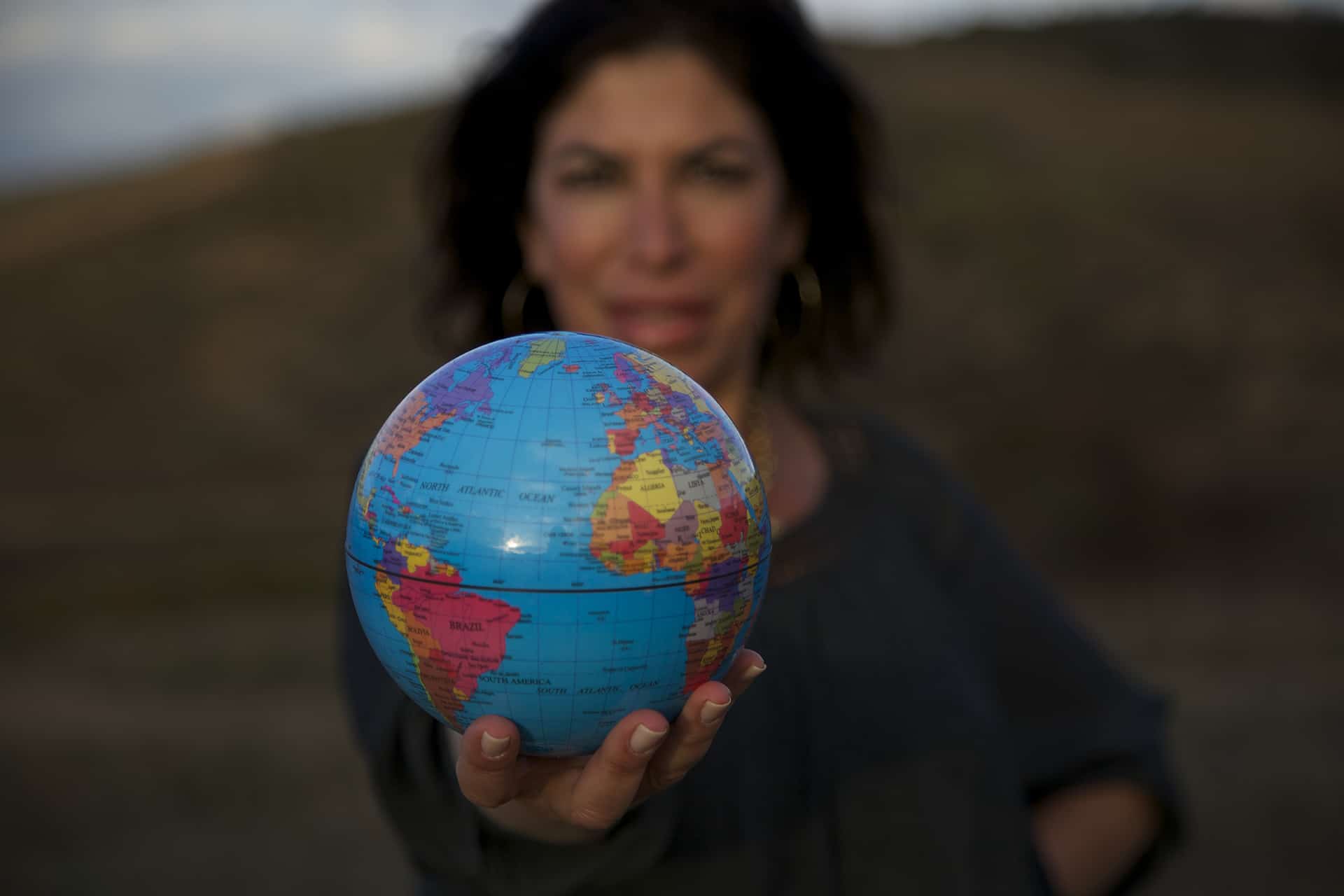 HHTR-About-header-temp Lisa Cypers Kamen, lifestyle consultant and expert in ptsd treatment, hoding a blue globe with a green background