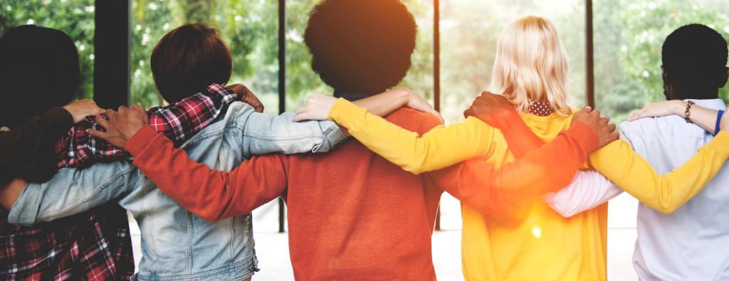 Teenagers holding together with orange, yellow, white and jean shirts while looking to the green forest, image of the page of life coach expert Lisa Cypers Kamen who develops programs of sustainable happiness and wellness.